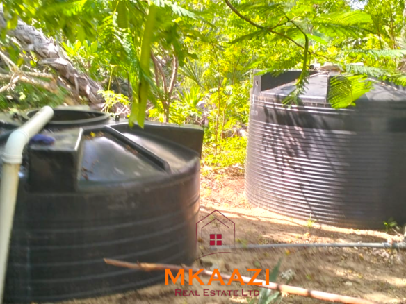 3-bedroom coastal home on 1-acre titled plot in Che Shale with solar panels, rainwater harvesting, balcony, and verandah. Expansion potential on adjoining 3/4-acre land.
