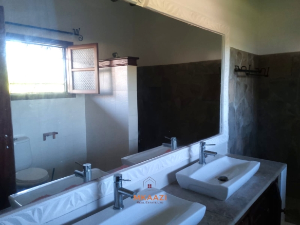Luxury 4-bedroom en-suite villa for sale near Marine Park Road Malindi with shared pool, private garden, and makuti roof.