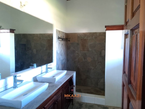 Luxury 4-bedroom en-suite villa for sale near Marine Park Road Malindi with shared pool, private garden, and makuti roof.