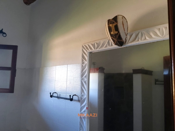 Luxury 4-bedroom en-suite villa for sale near Marine Park Road Malindi with shared pool, private garden, and makuti roof.