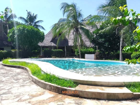 Luxury 4-bedroom en-suite villa for sale near Marine Park Road Malindi with shared pool, private garden, and makuti roof.