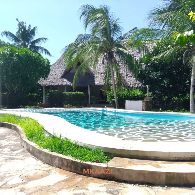 Luxury 4-bedroom en-suite villa for sale near Marine Park Road Malindi with shared pool, private garden, and makuti roof.