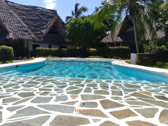 Luxury 4-bedroom en-suite villa for sale near Marine Park Road Malindi with shared pool, private garden, and makuti roof.