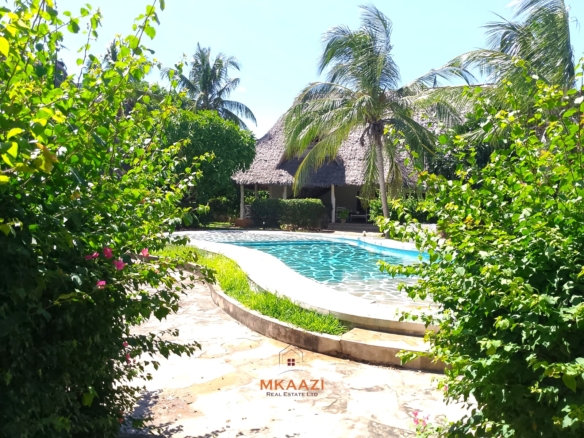Luxury 4-bedroom en-suite villa for sale near Marine Park Road Malindi with shared pool, private garden, and makuti roof.