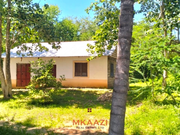 2-acre highway frontage property for sale in Matsangoni with house, shops, mature trees, and commercial investment potential.