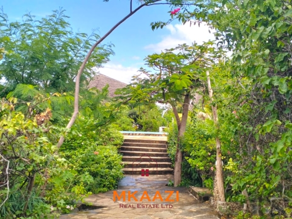 Luxury 4-bedroom house for sale in Mayungu, located in a secure gated community on the second row from the beach, featuring a shared swimming pool, landscaped garden, and serene coastal surroundings.