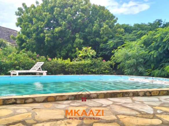 Luxury 4-bedroom house for sale in Mayungu, located in a secure gated community on the second row from the beach, featuring a shared swimming pool, landscaped garden, and serene coastal surroundings.