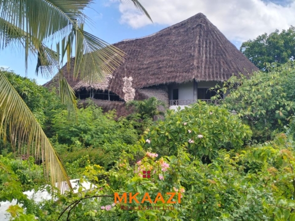 Luxury 4-bedroom house for sale in Mayungu, located in a secure gated community on the second row from the beach, featuring a shared swimming pool, landscaped garden, and serene coastal surroundings.