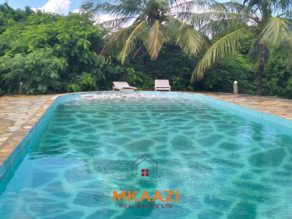 Luxury 4-bedroom house for sale in Mayungu, located in a secure gated community on the second row from the beach, featuring a shared swimming pool, landscaped garden, and serene coastal surroundings.
