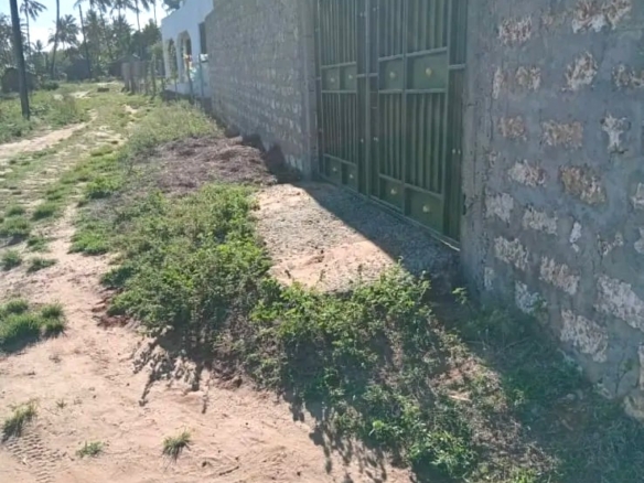 Secure flat plot for sale in Mavueni, Kilifi, featuring a coral stone perimeter wall, heavy gate and convenient access to the Malindi Highway and Kilifi Town.