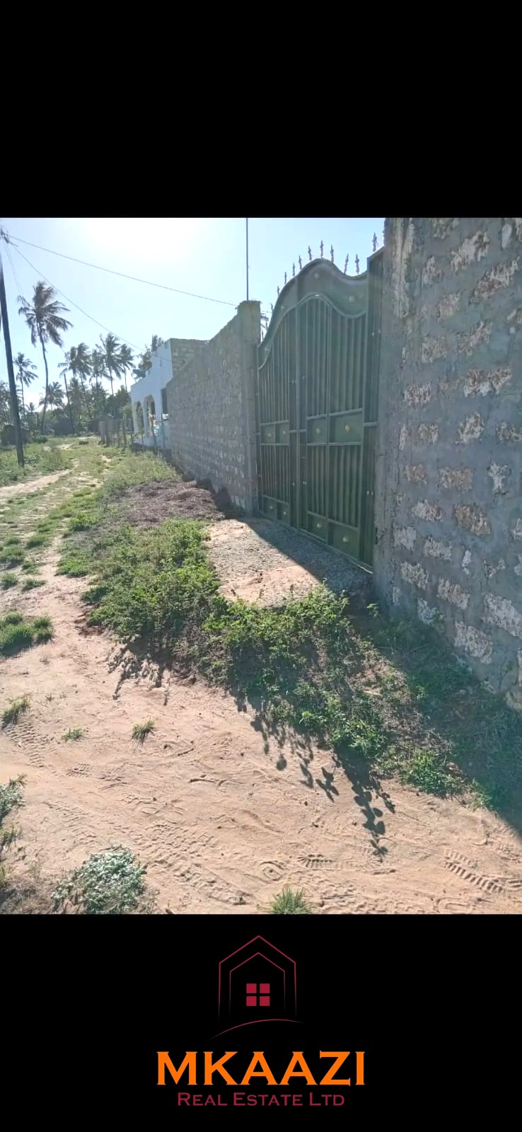 Secure flat plot for sale in Mavueni, Kilifi, featuring a coral stone perimeter wall, heavy gate and convenient access to the Malindi Highway and Kilifi Town.